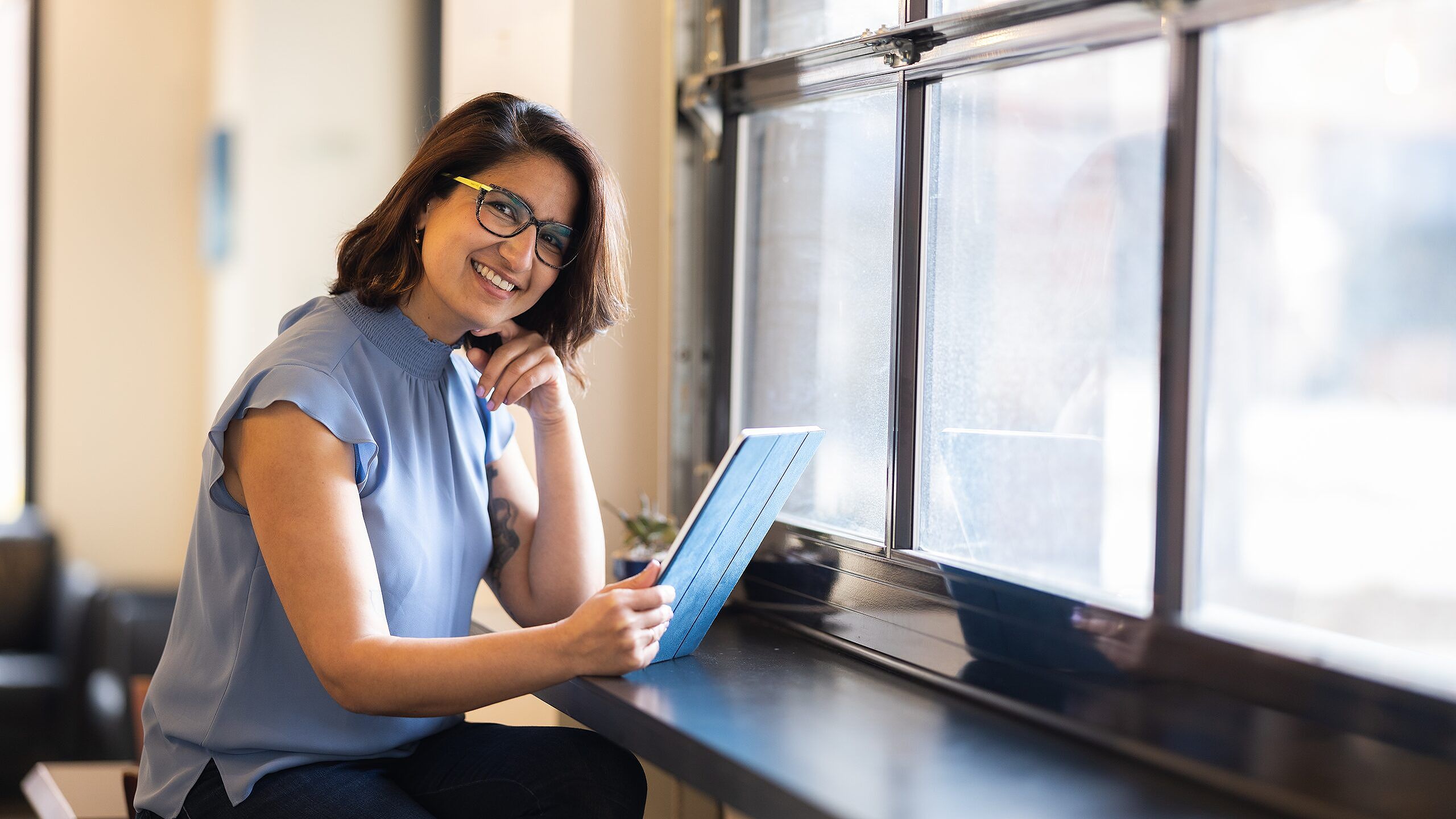 Woman sitting at table and holding tablet.